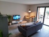 Coin salon avec canapé et télévision donnant accès à la terrasse
