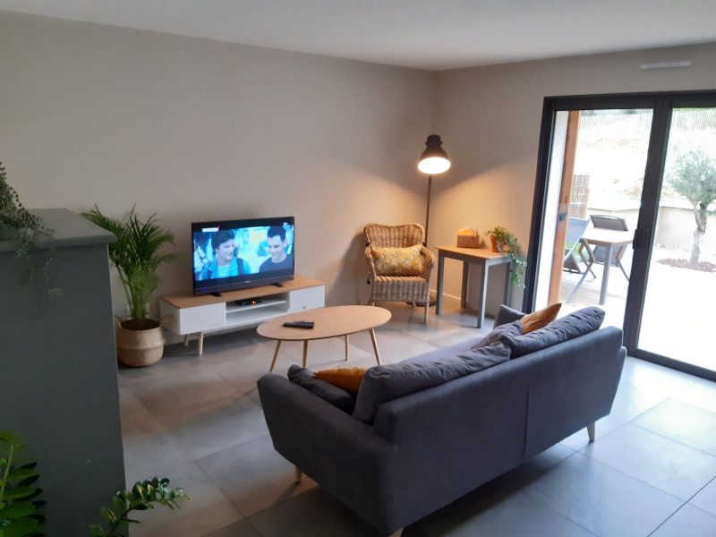 Coin salon avec canapé et télévision donnant accès à la terrasse