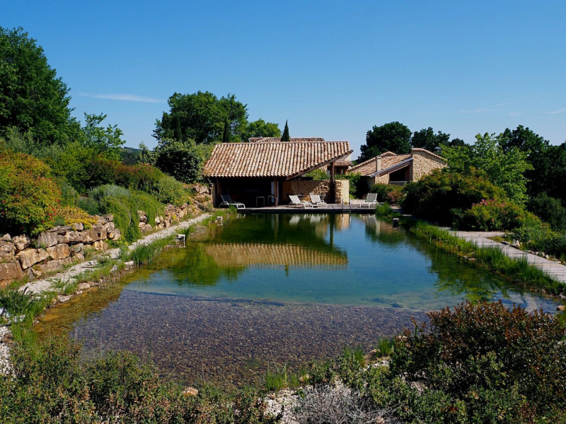 Bassin de baignade naturel partagé avec terrasse couverte et salon de jardin