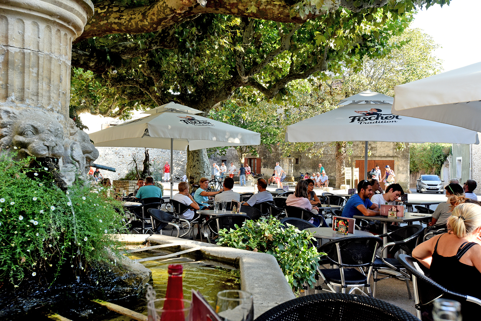 derrière la fontaine, on voit les cafés et terrasses animées en plein été