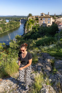 une jeune fille se promène sur les hauteurs d'Aiguèze, on aperçoit le village médiéval en arrière plan