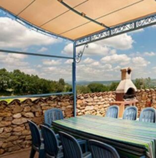 Grande terrasse ombragée avec table, chaises et barbecue