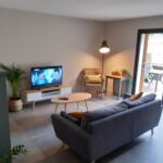 Coin salon avec canapé et télévision donnant accès à la terrasse