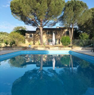 Vue sur la bâtisse, le jardin et la piscine