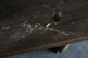 Domaine La Romance - Table gravée et un verre de vin rouge